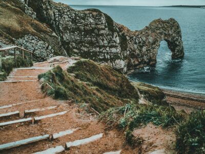Pathway leading to the iconic Durdle Door rock arch at West Lulworth, UK, with a scenic coastal view.